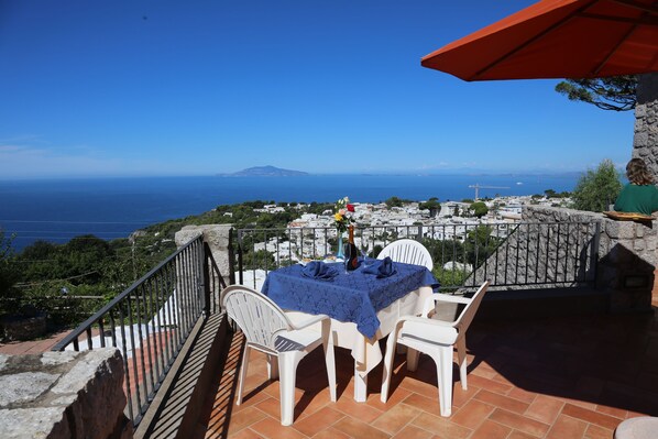 Une terrasse avec une table dressée pour deux personnes, donnant sur une ville côtière.