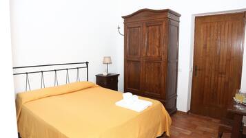Een kamer met een bed, een houten garderobe en een tafel met glazen.