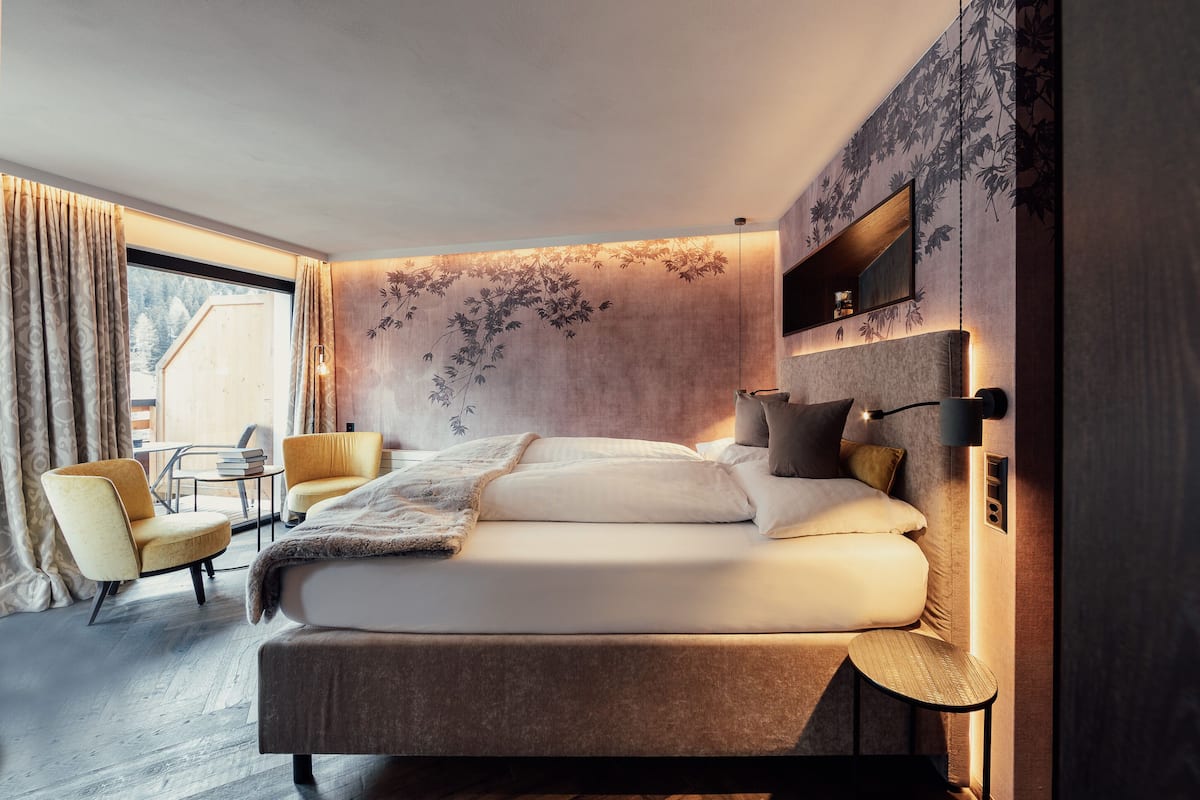 Un dormitorio moderno con una cama grande, una mesita de noche, una silla y una pequeña mesa con libros.
