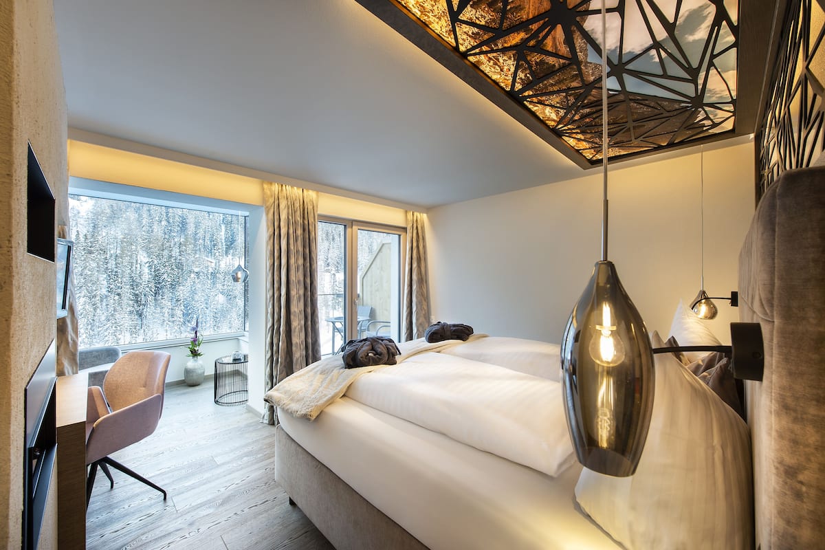 Un dormitorio moderno con una cama grande, un escritorio y una ventana con cortinas.