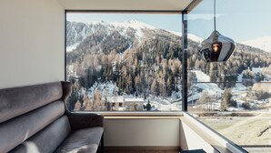 Una habitación moderna con un amplio ventanal que ofrece vistas a montañas nevadas y un área boscosa.