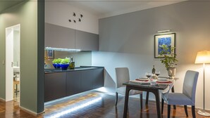 A modern kitchen with dark cabinets, a dining table set for two, and a small island with plants. - Belvedere Boutique - Adults Only (Funchal)
