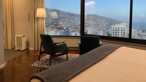 A hotel room with a large window, a bed, two chairs, a radiator, and a patterned rug. - Belvedere Boutique - Adults Only (Funchal)