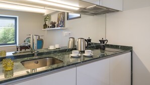 A modern kitchen with a stainless steel sink, a coffee maker, and a kettle. - Belvedere Boutique - Adults Only (Funchal)