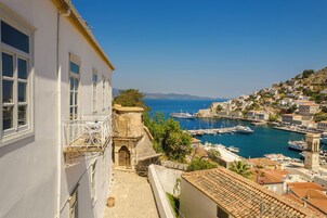 Un pueblo costero con un puerto deportivo, edificios blancos y una torre de piedra.