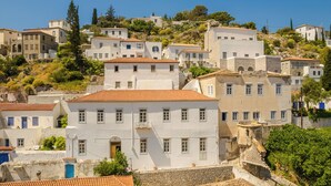 A hillside town with white buildings, red-tiled roofs, and a mix of stone and plaster facades. - Hydra Hotel (Hydra)