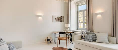 A modern living room with a sofa, a coffee table, a dining table with chairs, and a large window with curtains.
