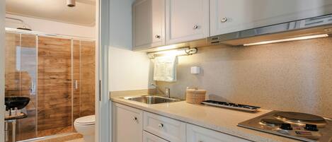 A modern kitchen with a built-in stove, a sink, and a glass shower enclosure.