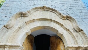 An arched doorway with wooden beams, a window, and a stone wall. - Hydrea Exclusive Hospitality (Hydra)