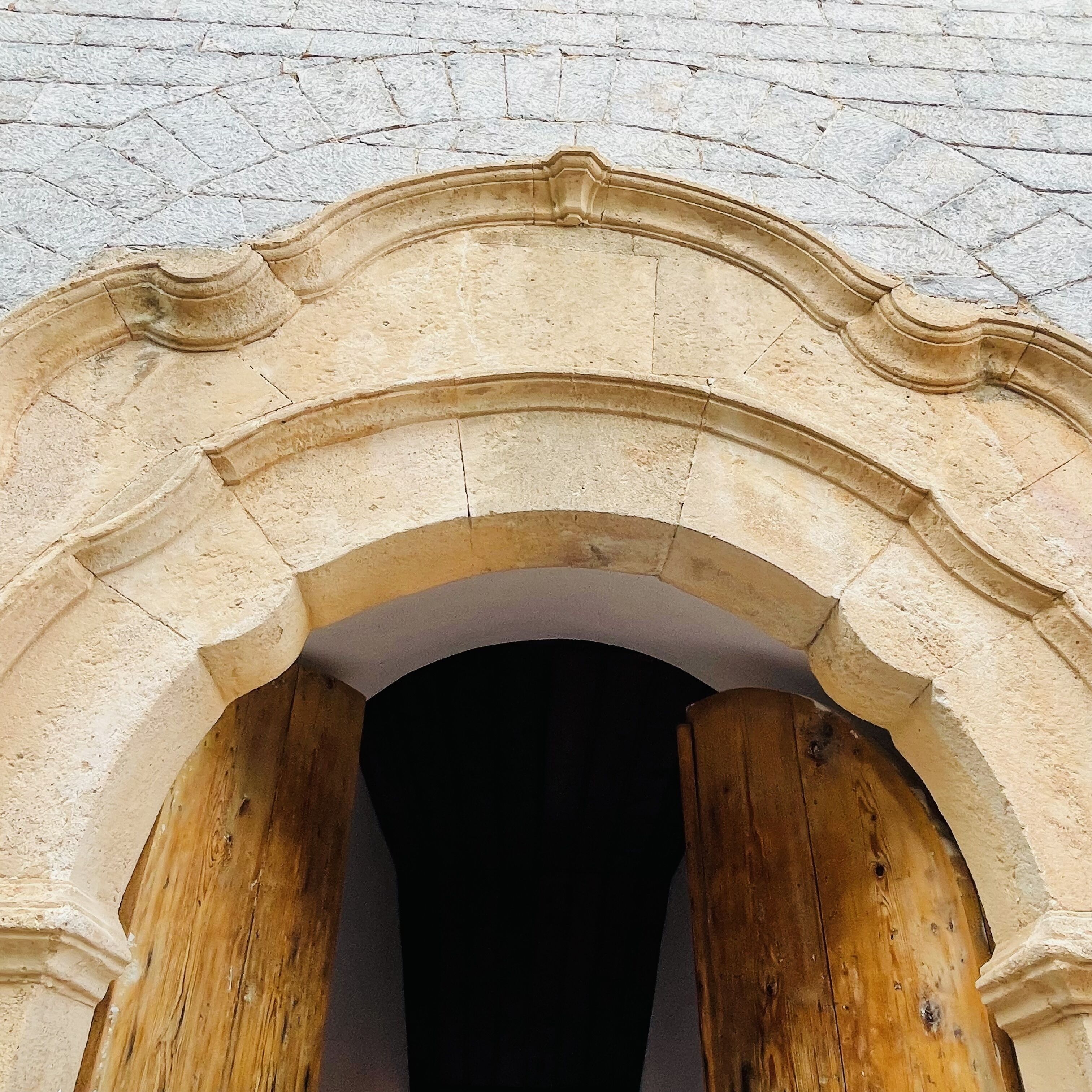 An arched doorway with a rough stone texture and wooden beams.