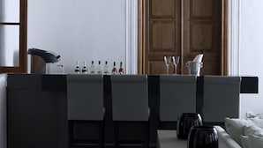 A modern kitchen with a wooden door, a built-in bar area with bar stools, and a tiled floor. - Hydrea Exclusive Hospitality (Hydra)