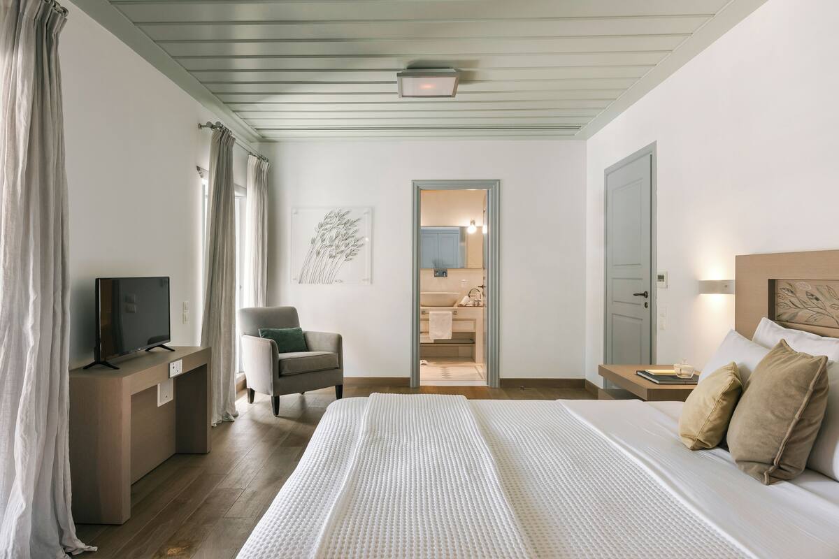 A hotel room with a bed, a desk, a chair, and a television.