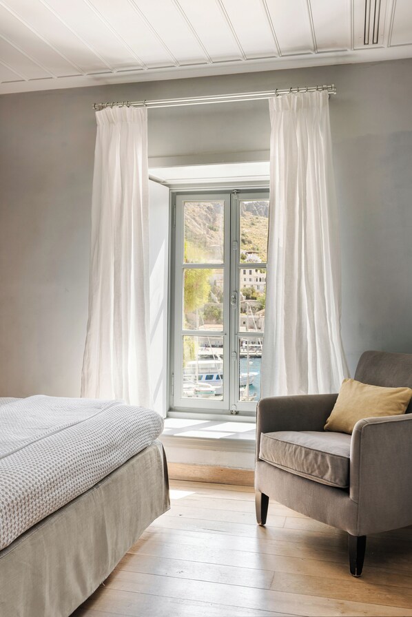 Un dormitorio con una cama, una silla y una ventana con cortinas.