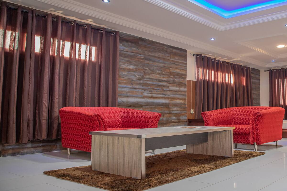 Un salon moderne avec deux fauteuils rouges, une table basse en bois et un canapé.