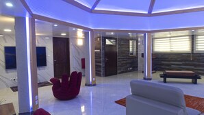 Un interior moderno con pared de mármol, una silla roja, un sofá y una puerta de madera.