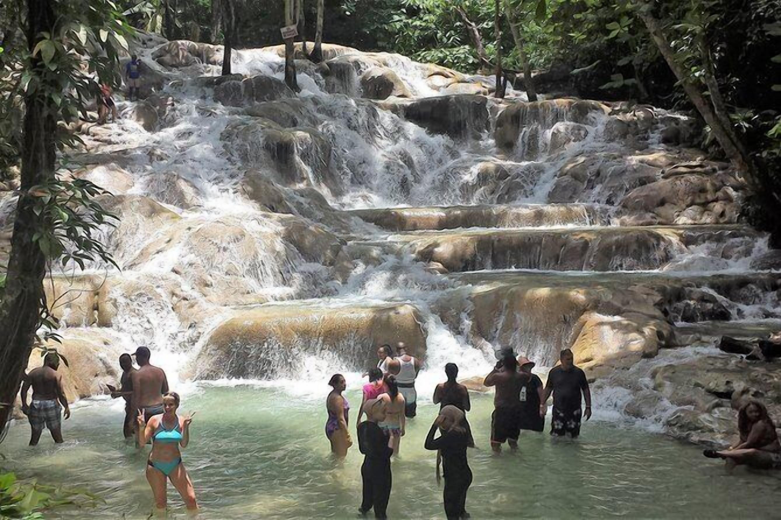 A natural water cascade surrounded by rocky terrain and lush greenery.
