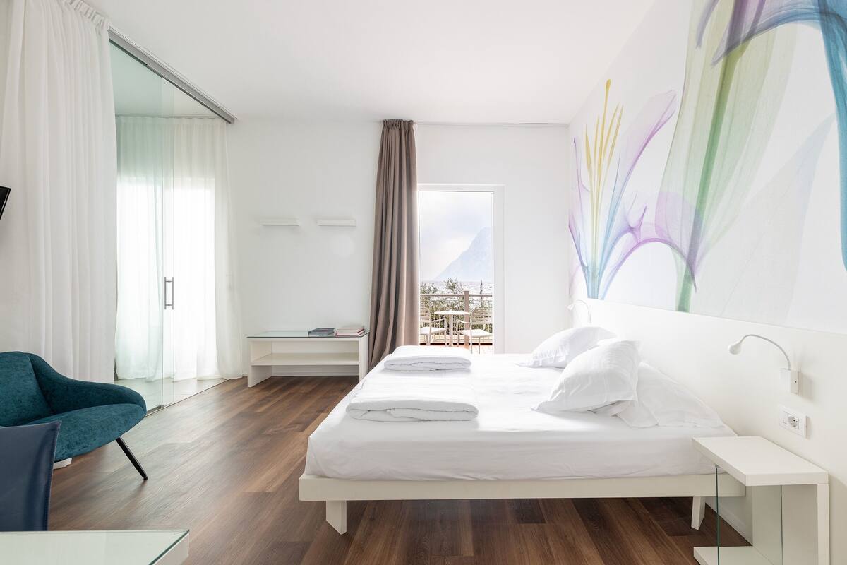 Habitación de hotel moderna con una cama, un escritorio, una silla y un ventanal con vistas.
