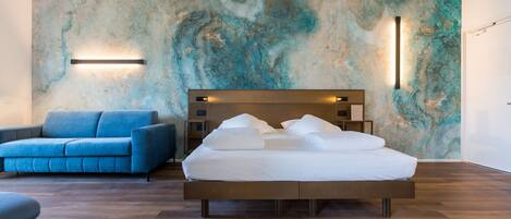 A modern bedroom with a large bed, a blue sofa, and a textured wall.