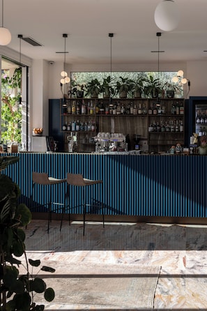 Eine Bar mit Sitzgelegenheiten, einem Marmorboden und Blick auf Grünflächen.
