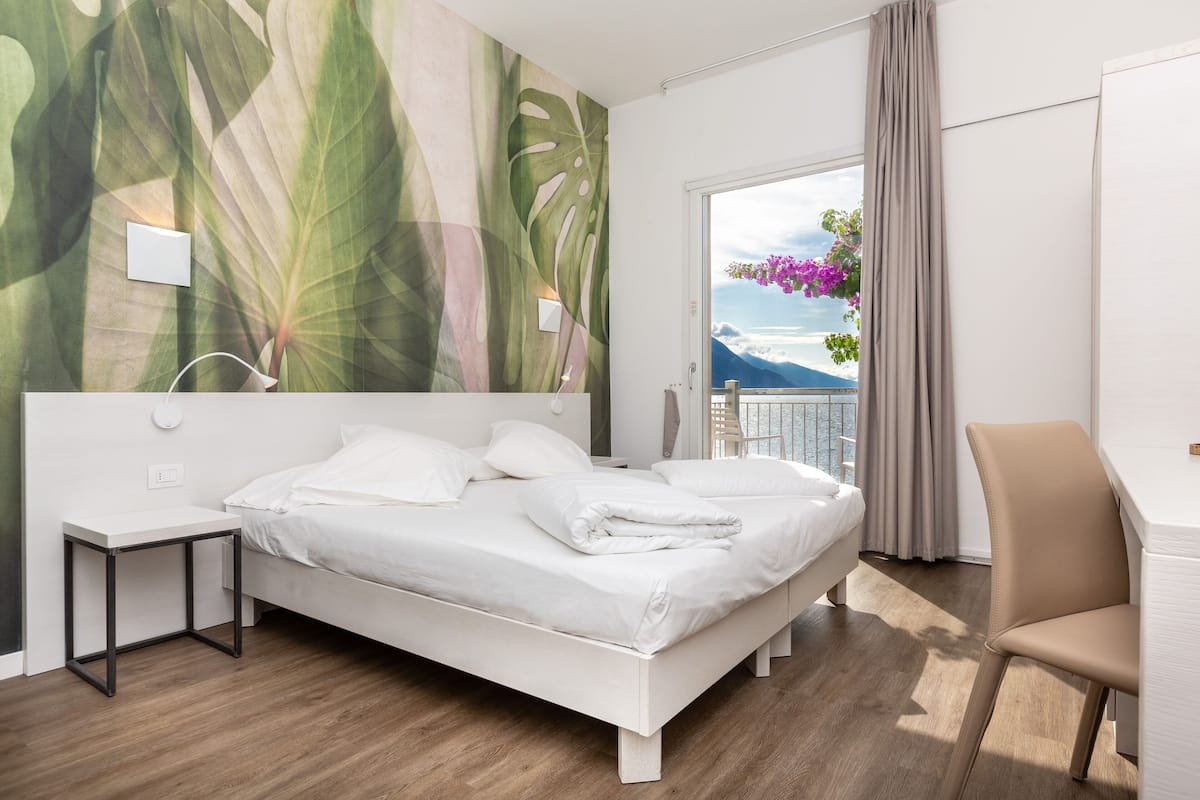 Una habitación de hotel moderna con una cama, un escritorio y vistas al océano.