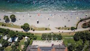 Vista aérea de una playa con gente, tiendas de campaña y vehículos recreativos.