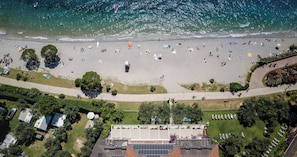 Une vue aérienne d’une plage où l’on aperçoit des personnes, des tentes et des camping-cars.