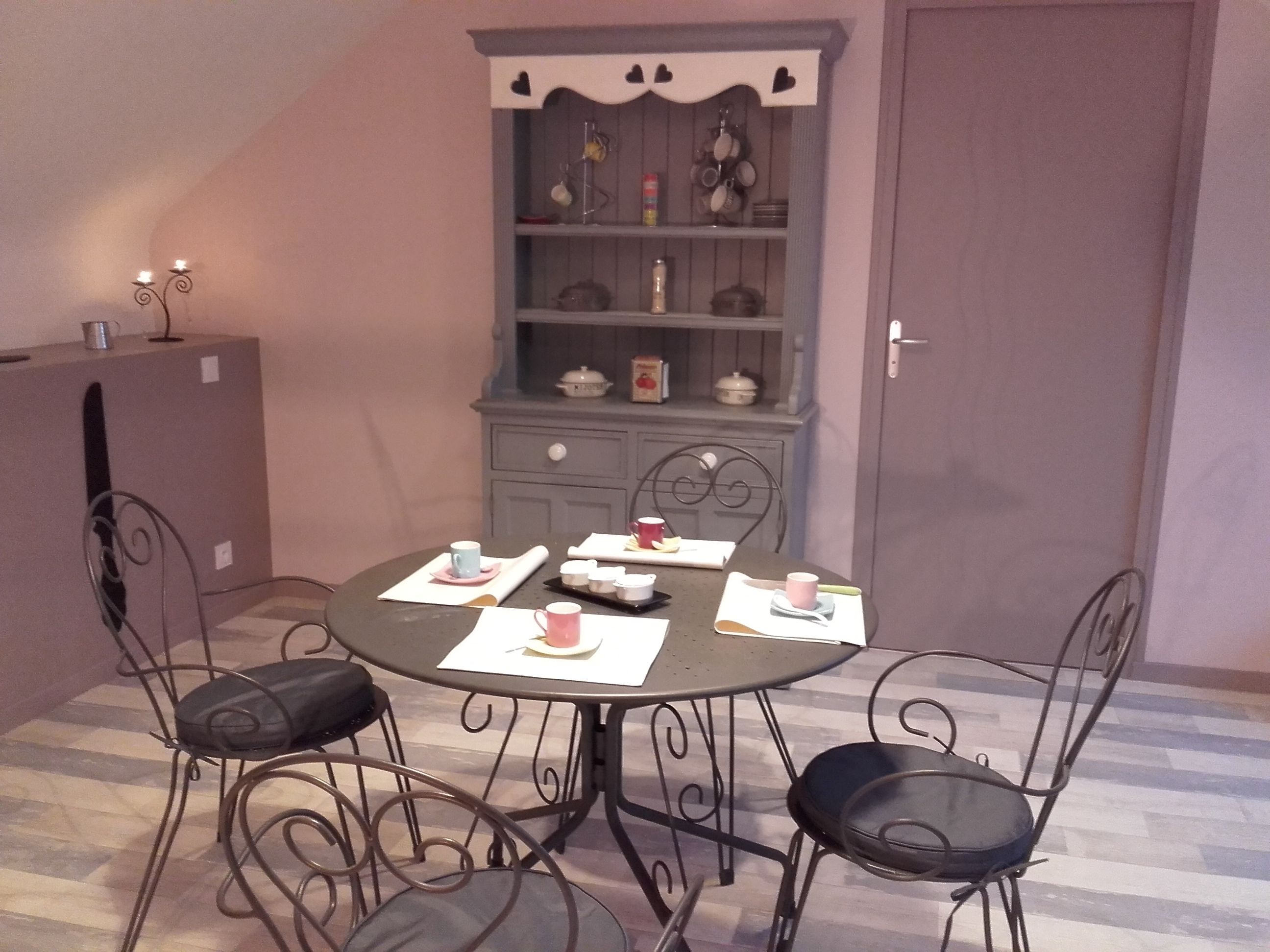 A dining area with a round table, four chairs, and a cabinet with shelves.