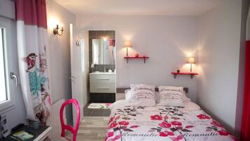 A bedroom with a bed, a chair, a desk, and a mirror.