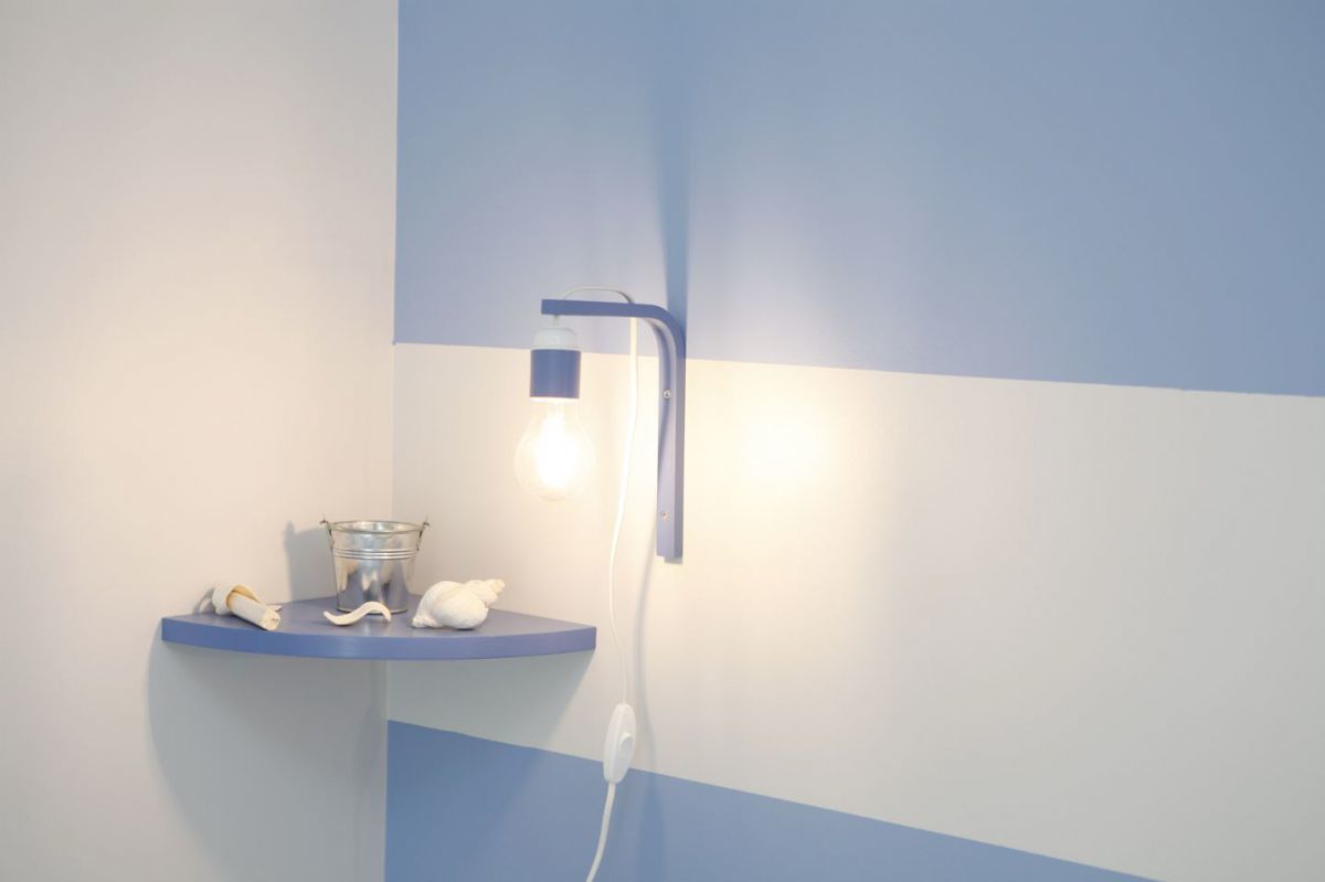 Een badkamer met blauw-wit kleurenschema, een wastafel met glazen kom, een witte handdoek en een wandlamp.