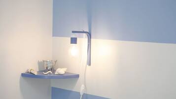 Een badkamer met blauw-wit kleurenschema, een wastafel met glazen kom, een witte handdoek en een wandlamp.