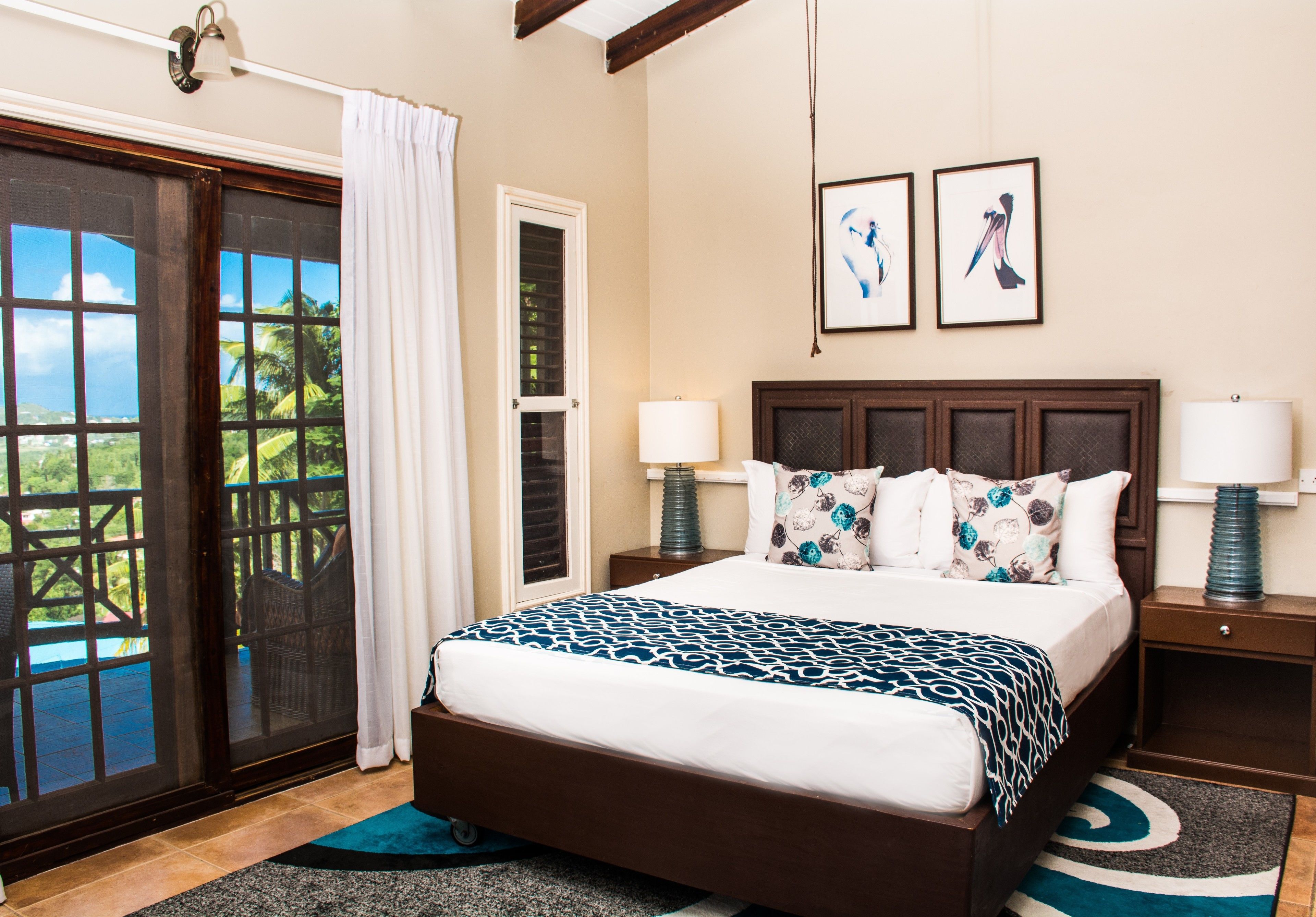 A hotel room with a large bed, two bedside tables, a window with a view, and a door leading to a balcony.
