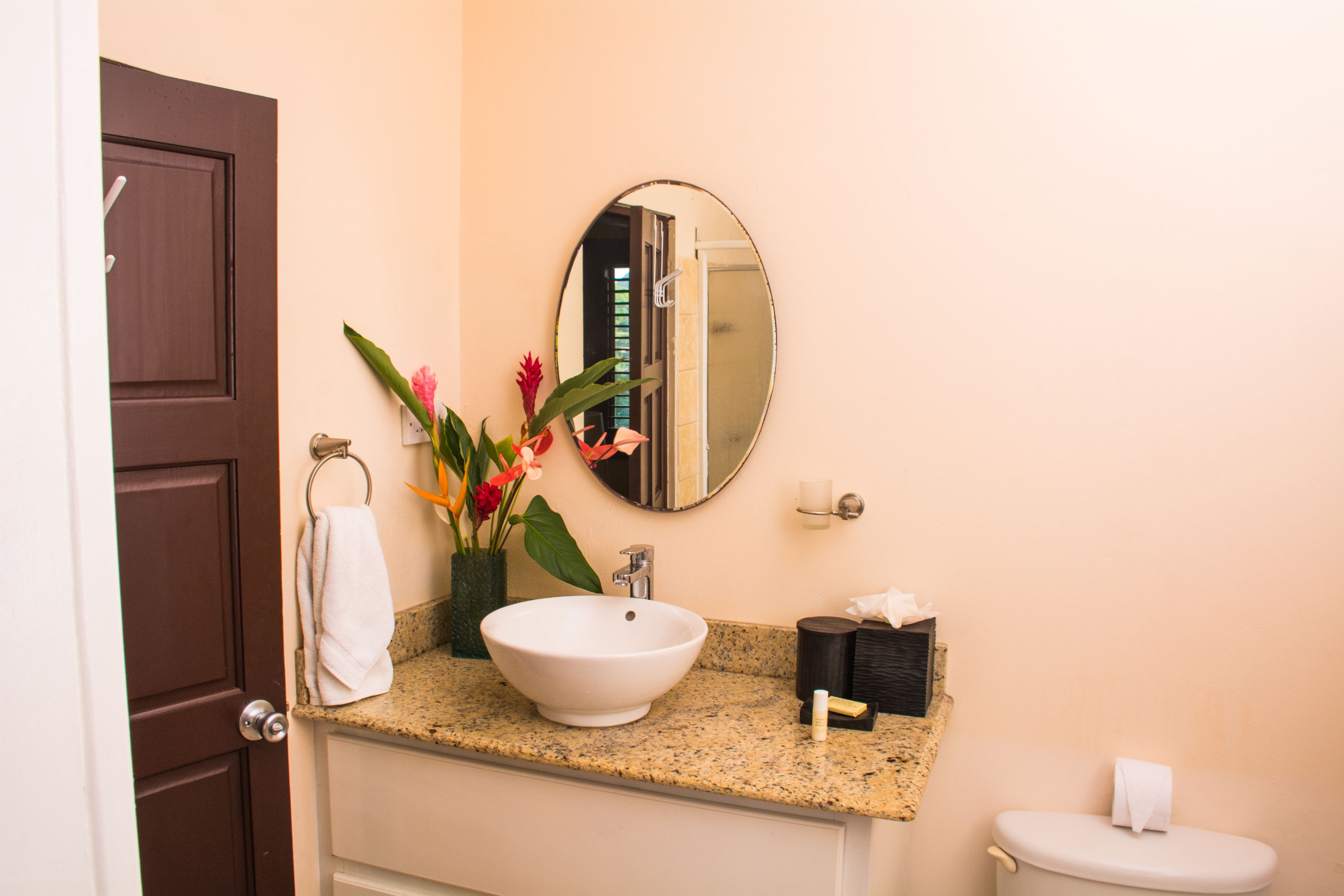 A bathroom with a white sink, a mirror, a toilet, and a door.