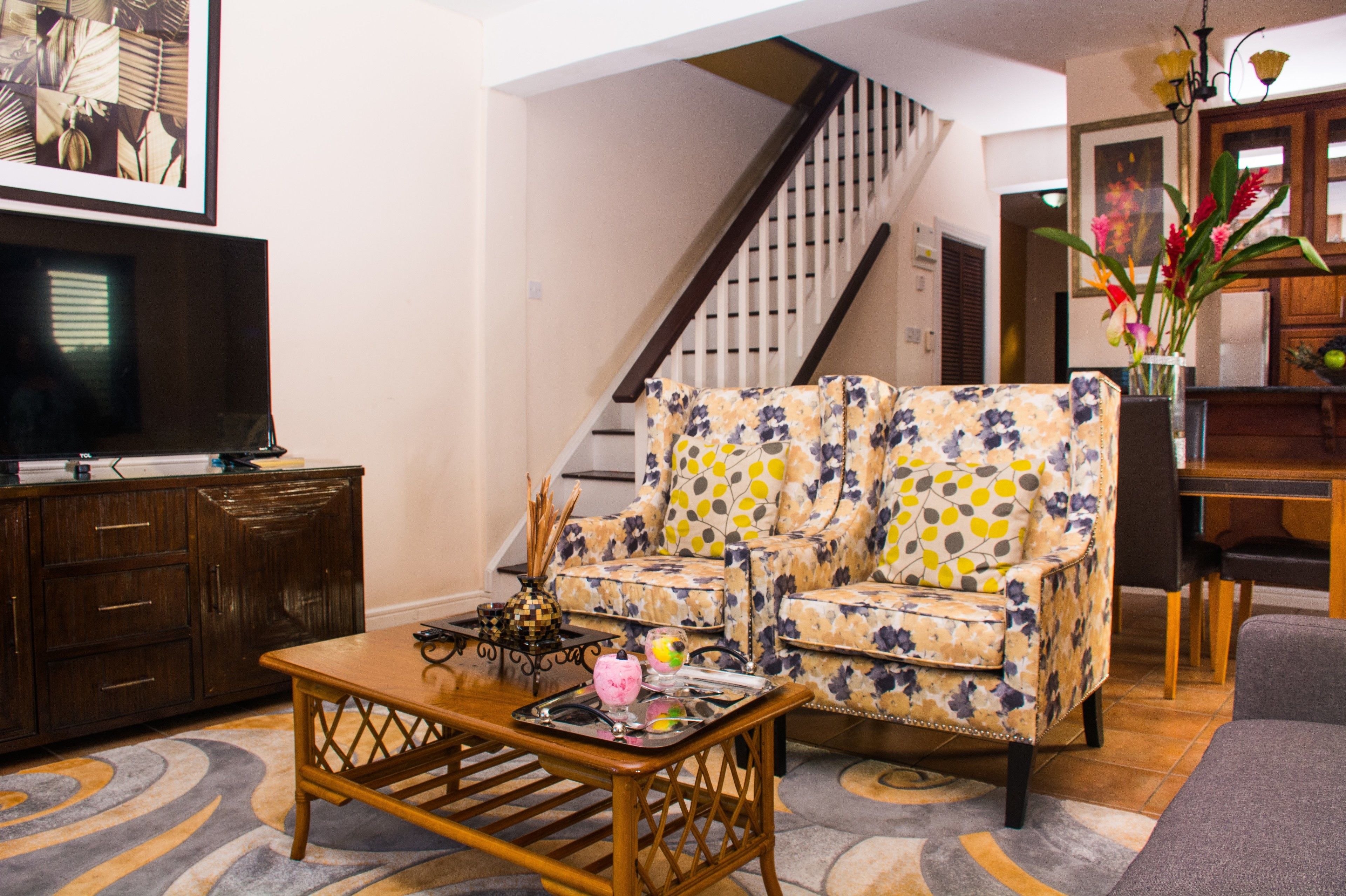 A living room with a sofa, a coffee table, a TV, and a staircase.