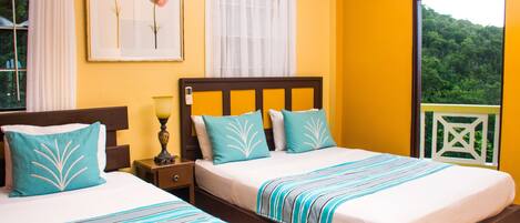 A hotel room with two beds, a window with a view of greenery, and a framed picture on the wall.