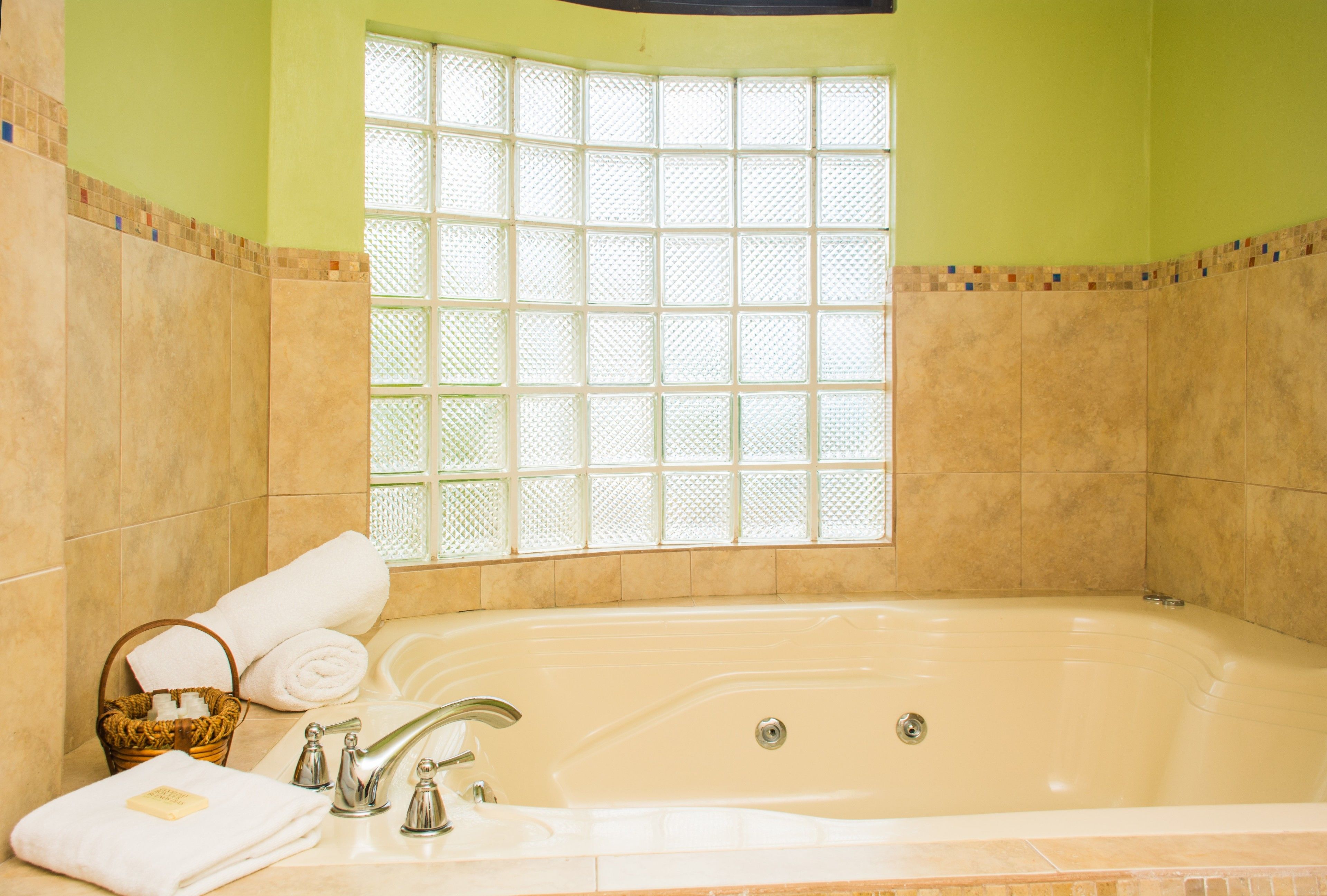 A bathroom with a large bathtub, a window with a grid pattern, and a basket with towels.