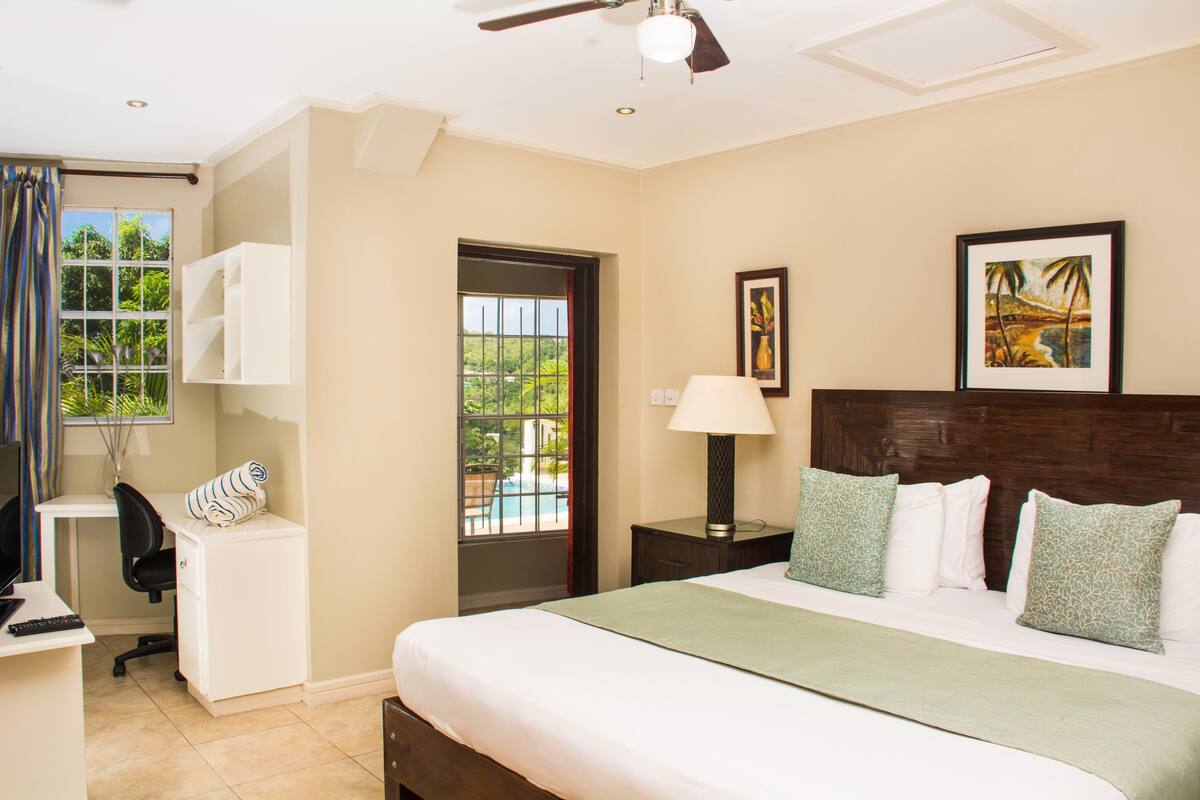 Ein Hotelzimmer mit Bett, Schreibtisch, Stuhl und Blick ins Freie.
