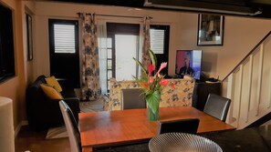 A living room with a wooden dining table, a sofa, and a TV. - Heavenly Suites (Gros Islet)