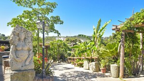 Une sculpture en pierre, un sentier et une végétation luxuriante dans un jardin.