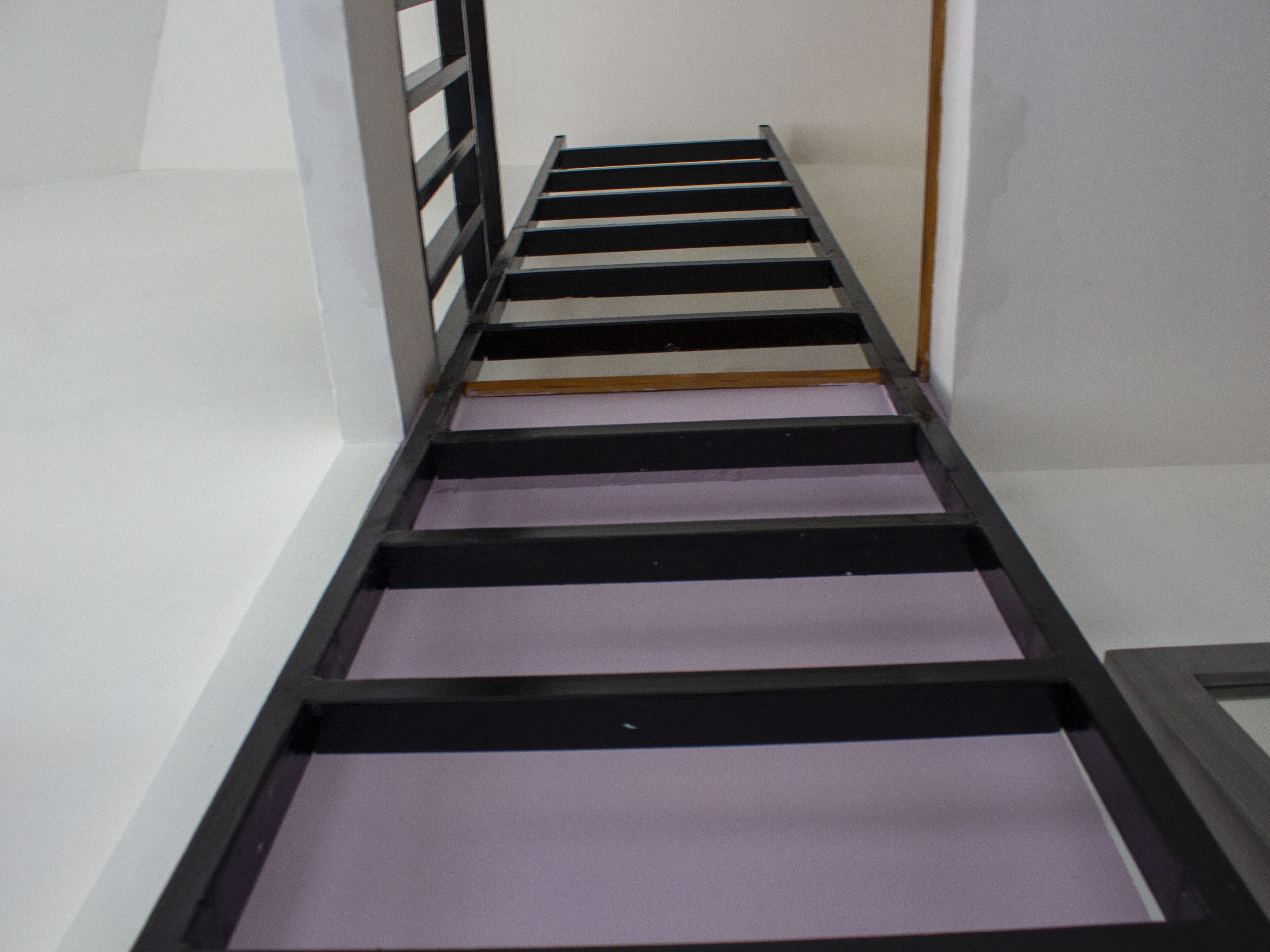 A narrow hallway with a black metal staircase leading to a landing.