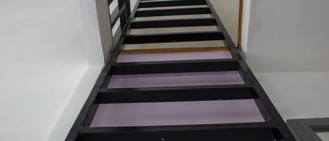 A narrow hallway with a black metal staircase leading to a landing.