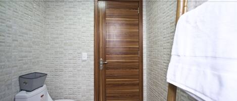 Un baño con puerta de madera, inodoro y un perchero para toallas.
