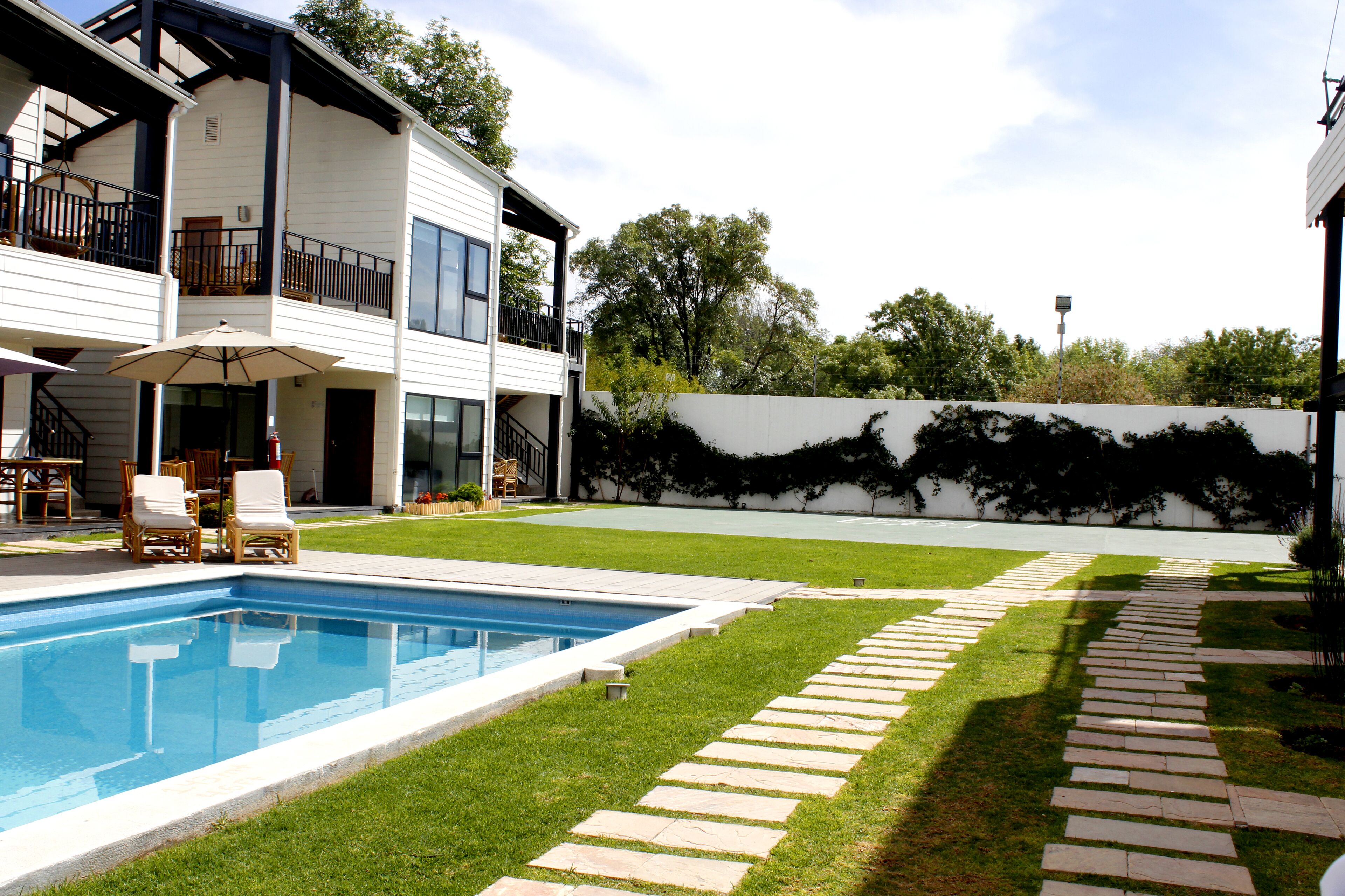 Ein modernes, zweistöckiges Haus mit Swimmingpool, gepflasterter Terrasse und einem Kiesweg.