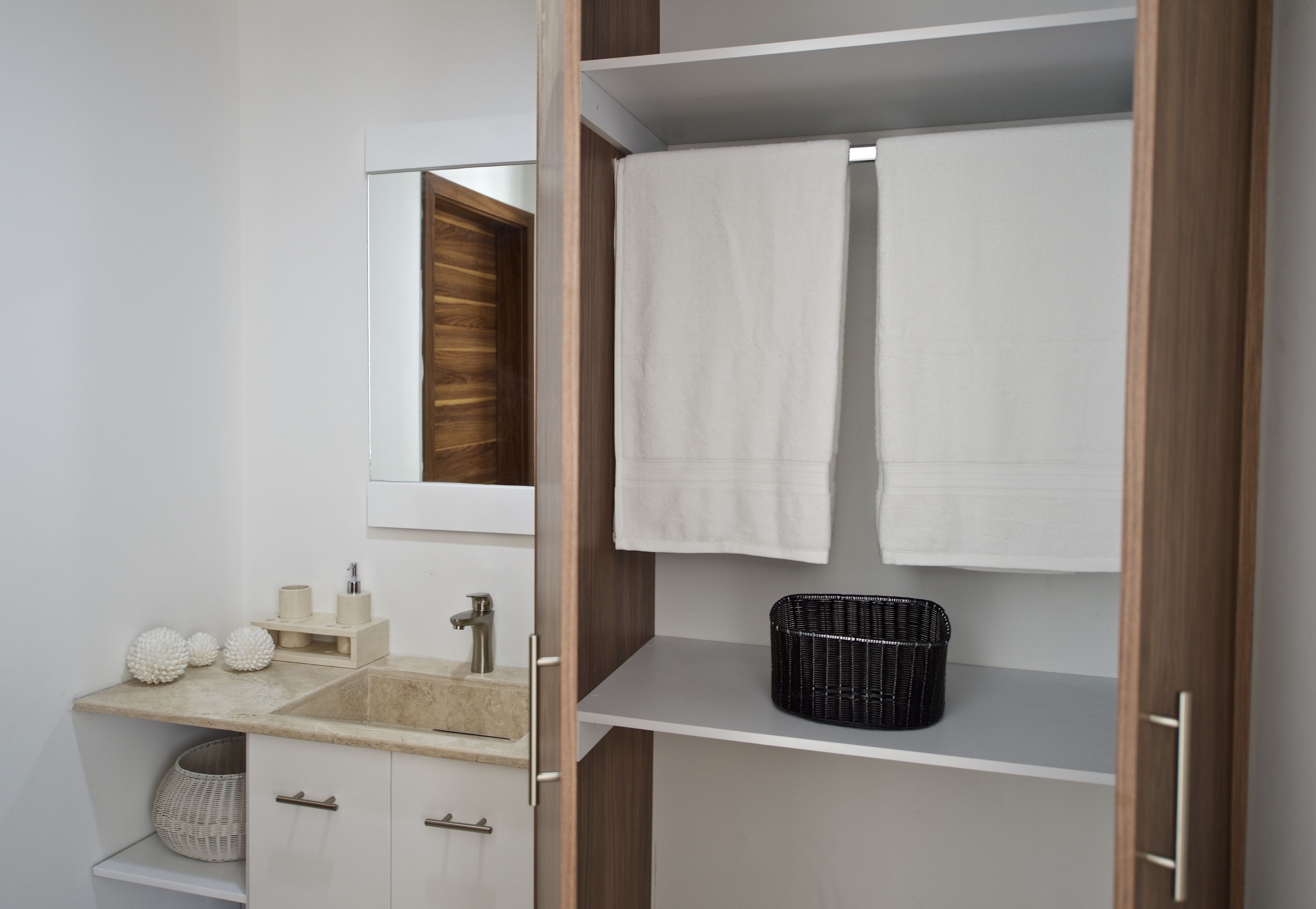Une salle de bain équipée d’un lavabo, d’un miroir, d’un porte-serviettes et d’étagères de rangement.