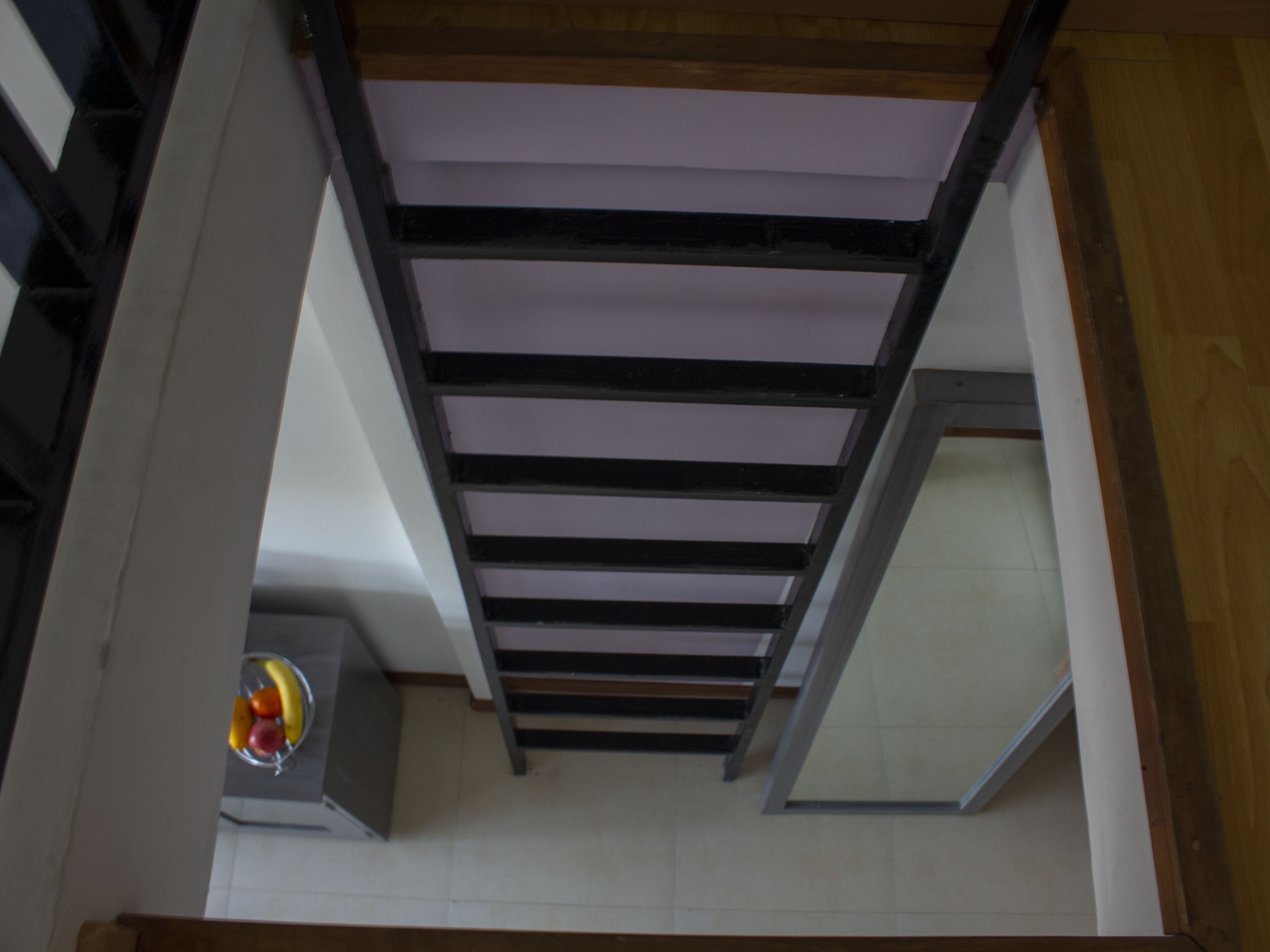 A view of a staircase with a wooden beam ceiling and a tiled floor.