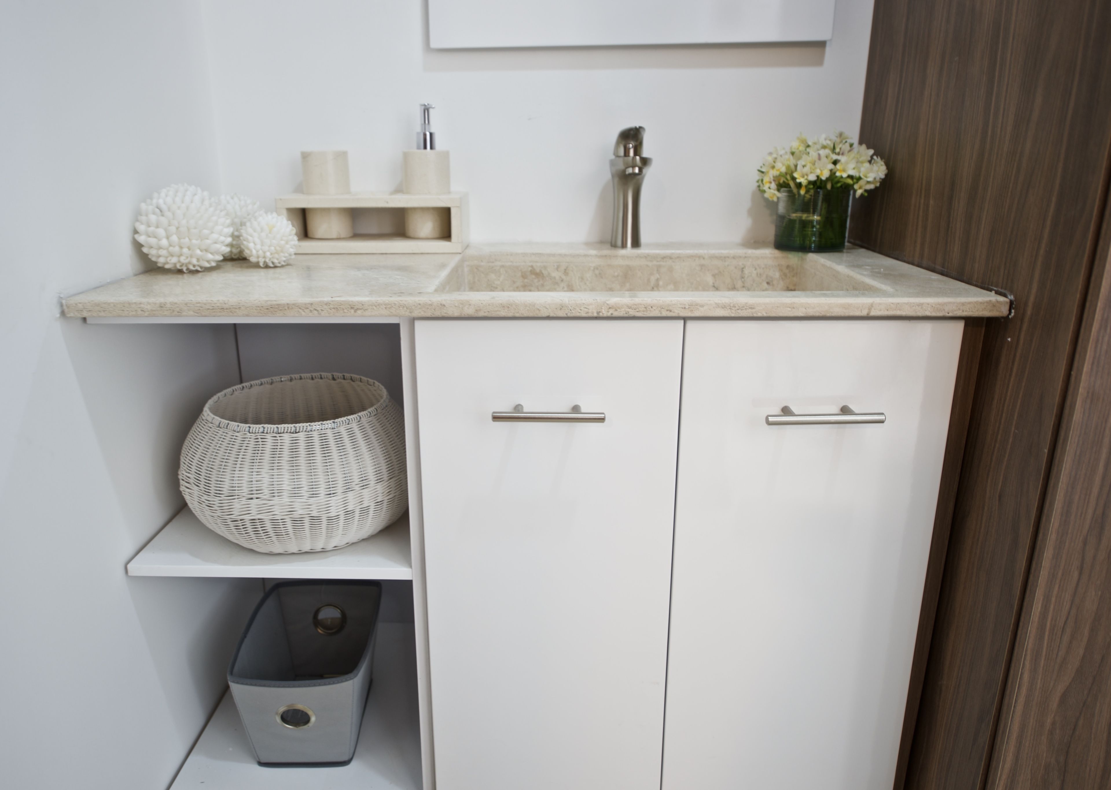 A modern kitchen with white cabinets, a marble countertop, a sink, and a small basket.
