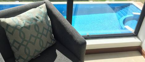 A room with a view of a swimming pool through a large window.