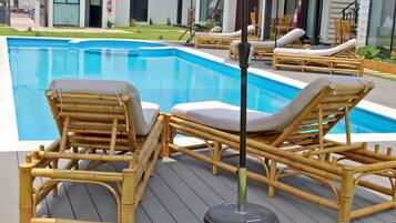 Zona junto a la piscina con sillones de descanso de bambú y un extintor.