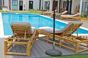 Zona junto a la piscina con sillones de descanso de bambú y un extintor.
