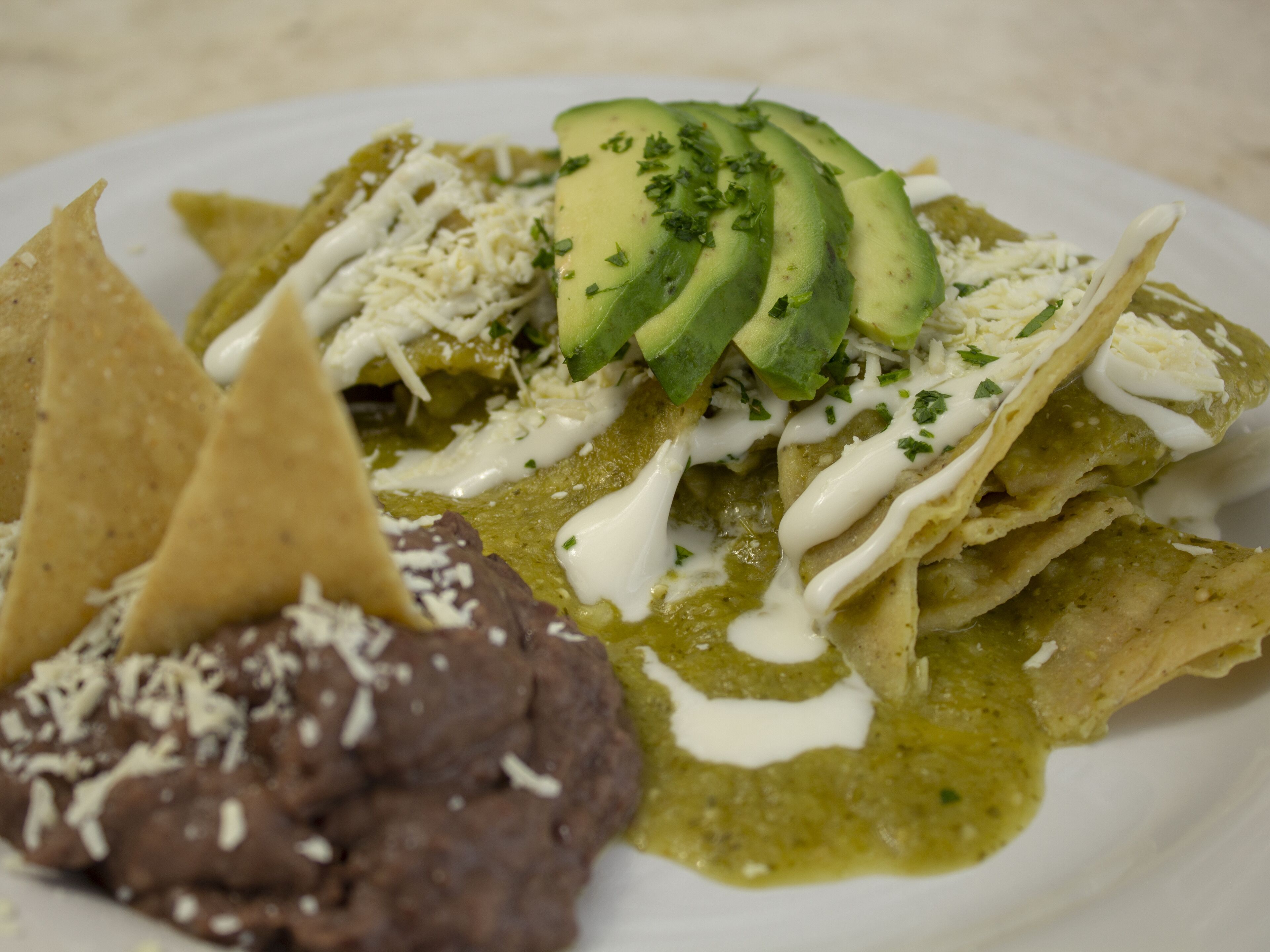 Un plato de nachos con guacamole, crema agria y queso.