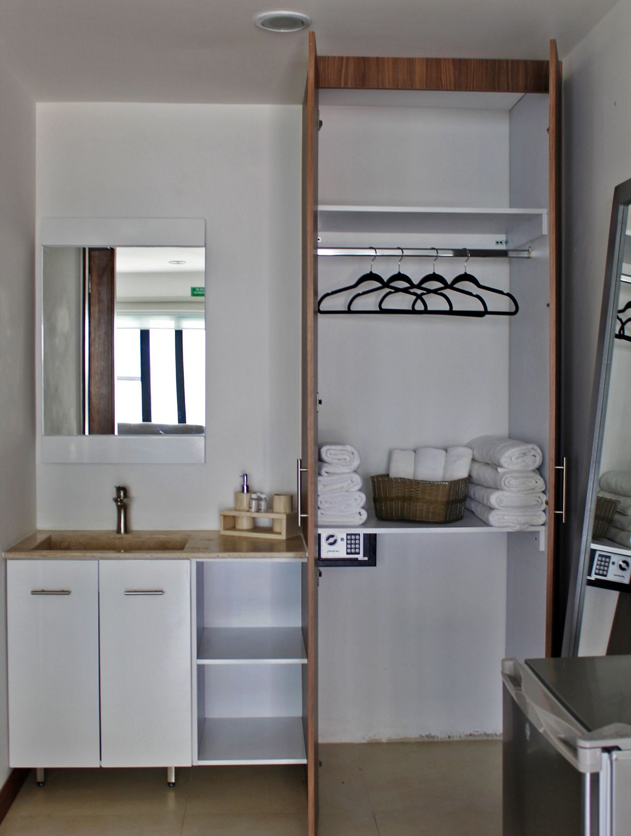 A bathroom with a sink, mirror, and towel storage.